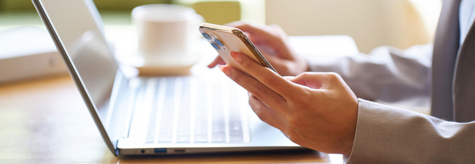 one hand holing a smartphone while the other uses a laptop